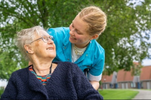 Vrouw duwt andere vrouw in rolstoel en kijkt haar aan Vrouw duwt andere vrouw in rolstoel en kijkt haar aan